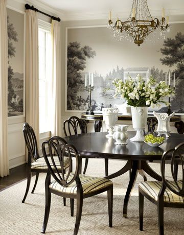 a dining room table with chairs and vases on it in front of a wall mural