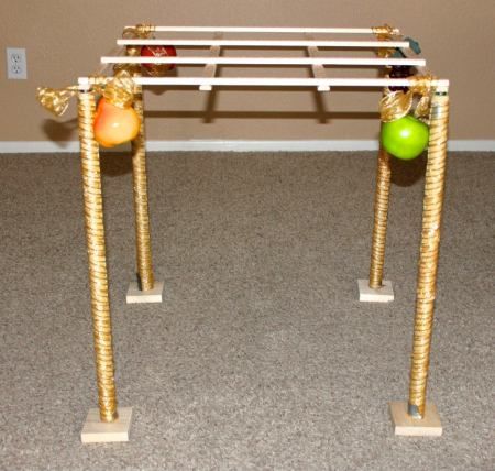 two metal poles with apples and oranges on them in front of a brown wall