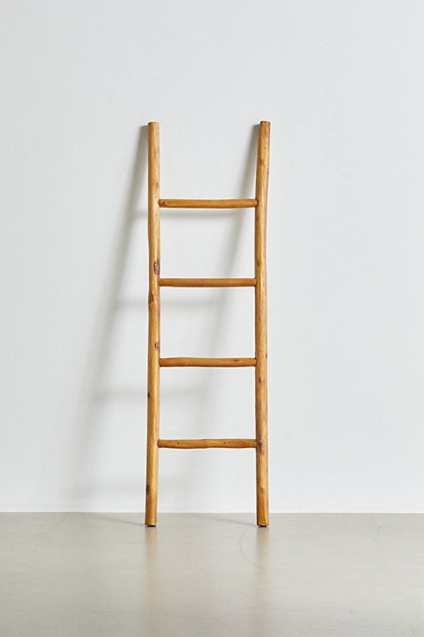 a wooden ladder leaning against a white wall