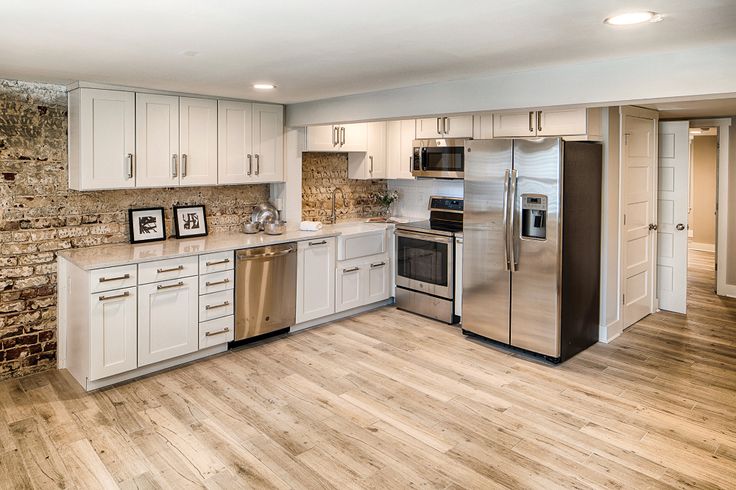 an empty kitchen with white cabinets and stainless steel appliance, wood flooring