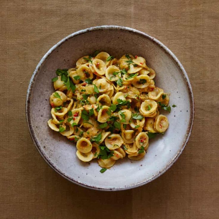 a white bowl filled with pasta on top of a wooden table