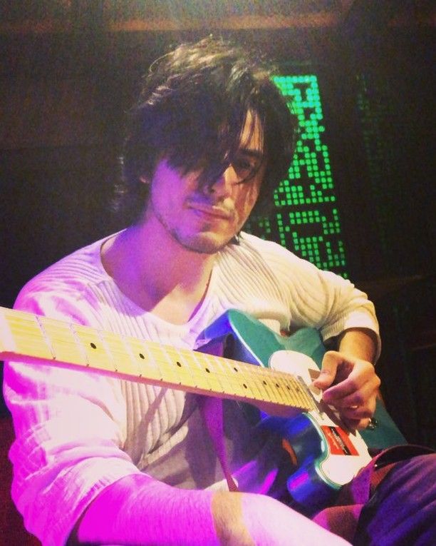 a man sitting down playing an electric guitar