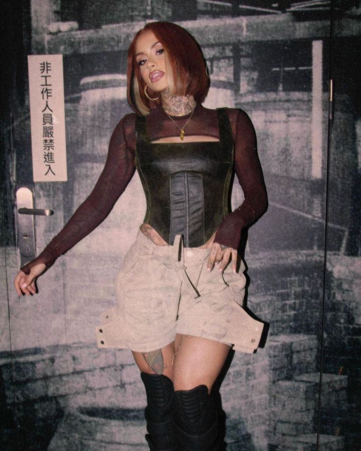 a woman in short skirt and boots standing next to a wall with writing on it