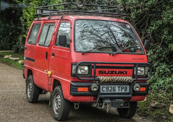 a red van parked on the side of a road next to some bushes and trees