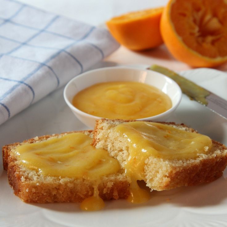 two slices of bread on a plate with oranges in the background and a knife