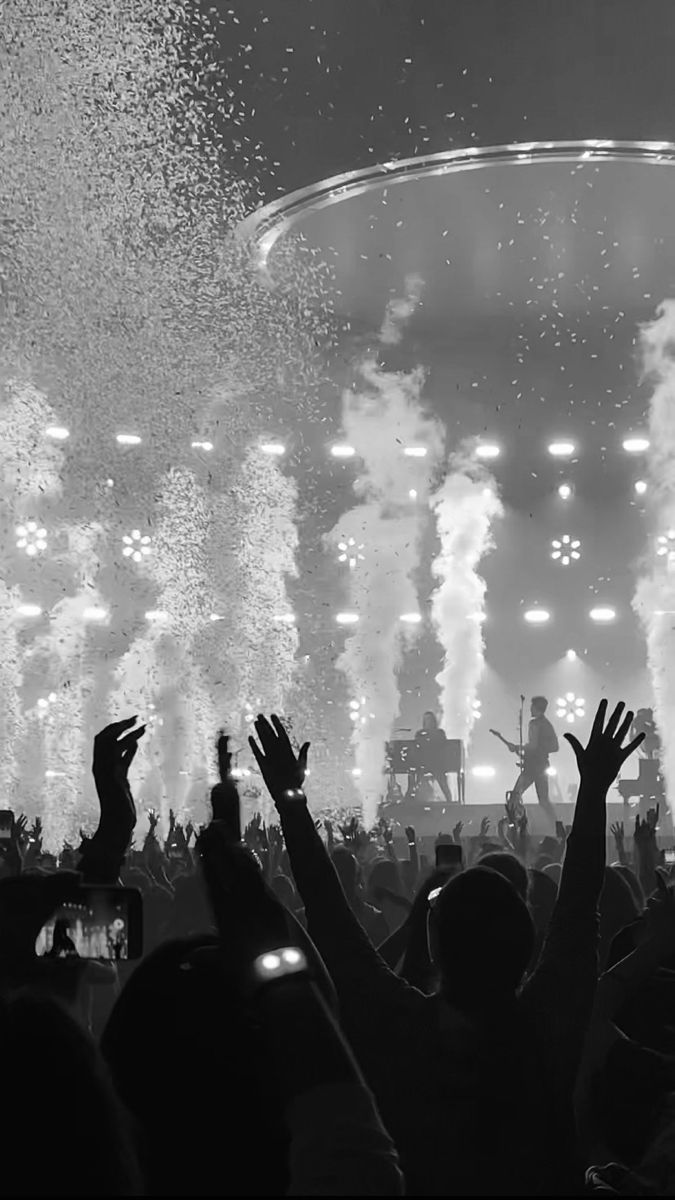 people are watching fireworks go off in the air at a music concert with their hands up