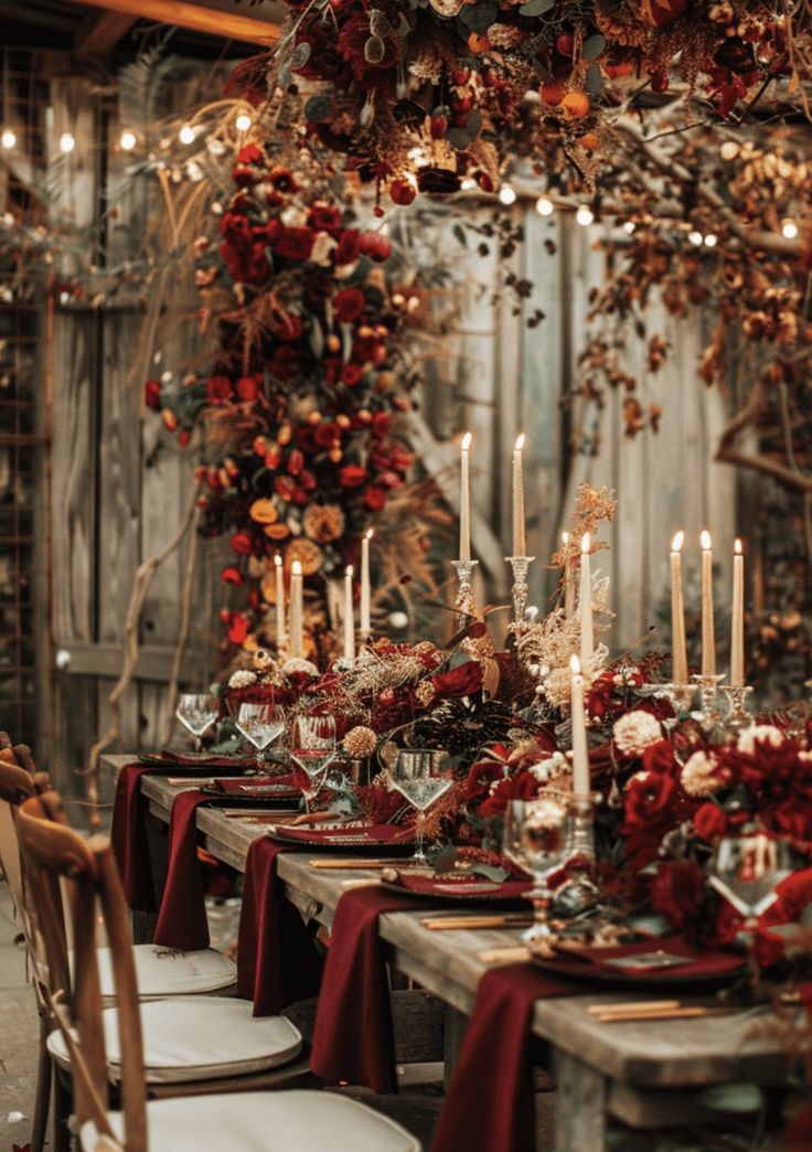 the table is set with red and gold flowers, candles, and napkins on it