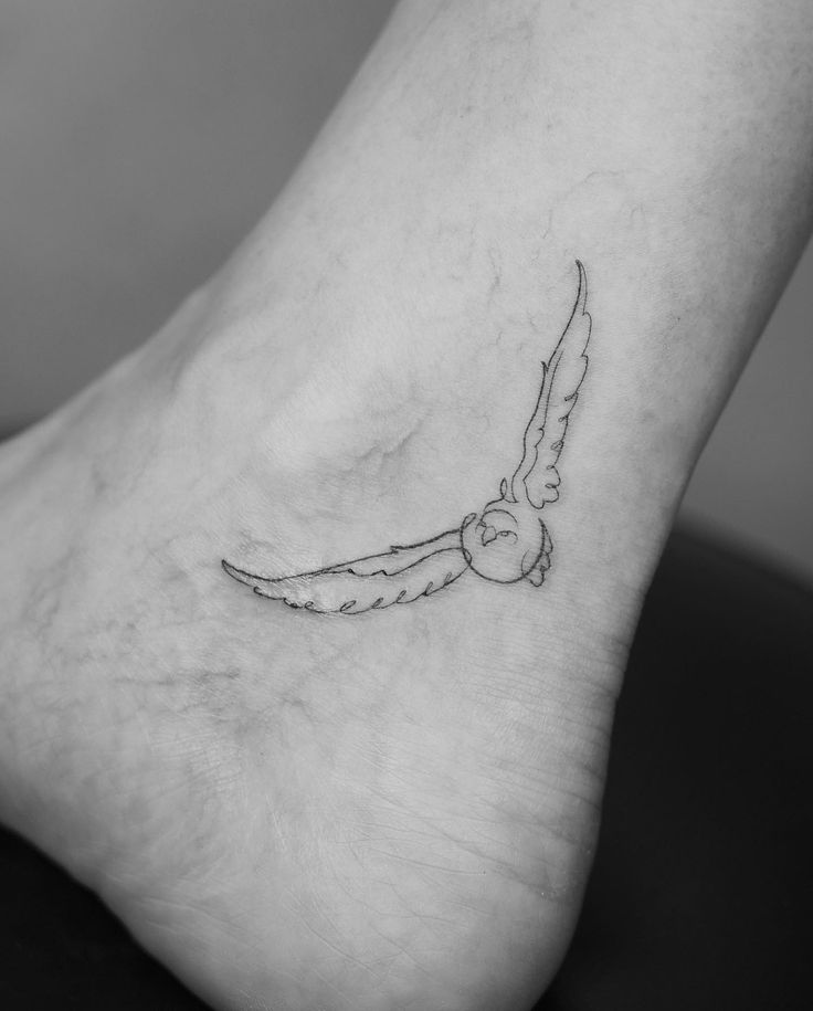 a small tattoo on the foot of a person with a bird flying over it's head