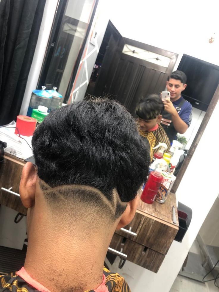 a man sitting in front of a mirror while getting his hair cut at a barbershop