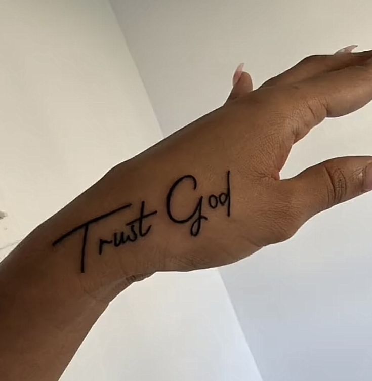 a person's hand with the word trust god written on it, in black ink