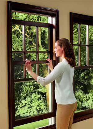 a woman standing in front of a window looking out at the trees outside her house