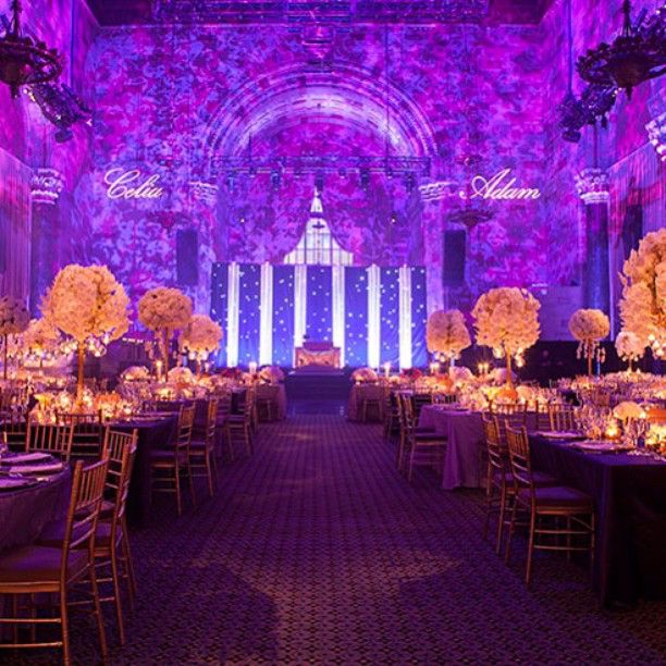 an elaborately decorated ballroom with purple lighting and floral centerpieces on the tables