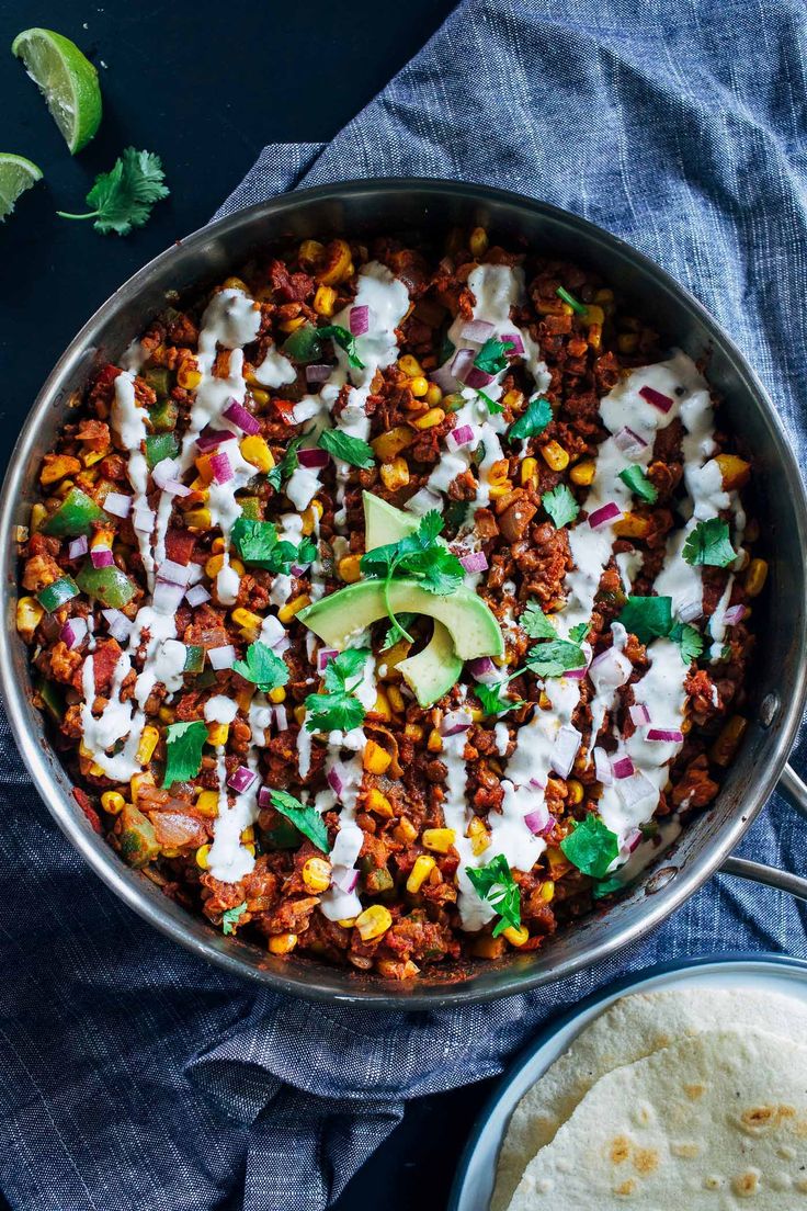 a skillet filled with taco salad and tortilla chips on a blue towel