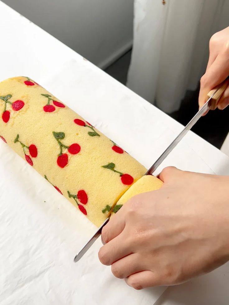 a person cutting into a cake with a large knife on it's end and covered in cherries