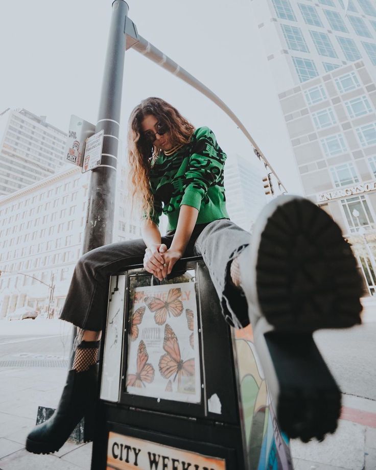 a woman sitting on top of a street light pole next to a sign that says city weekly