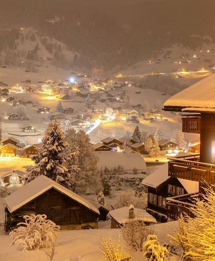 a snow covered town at night in the mountains