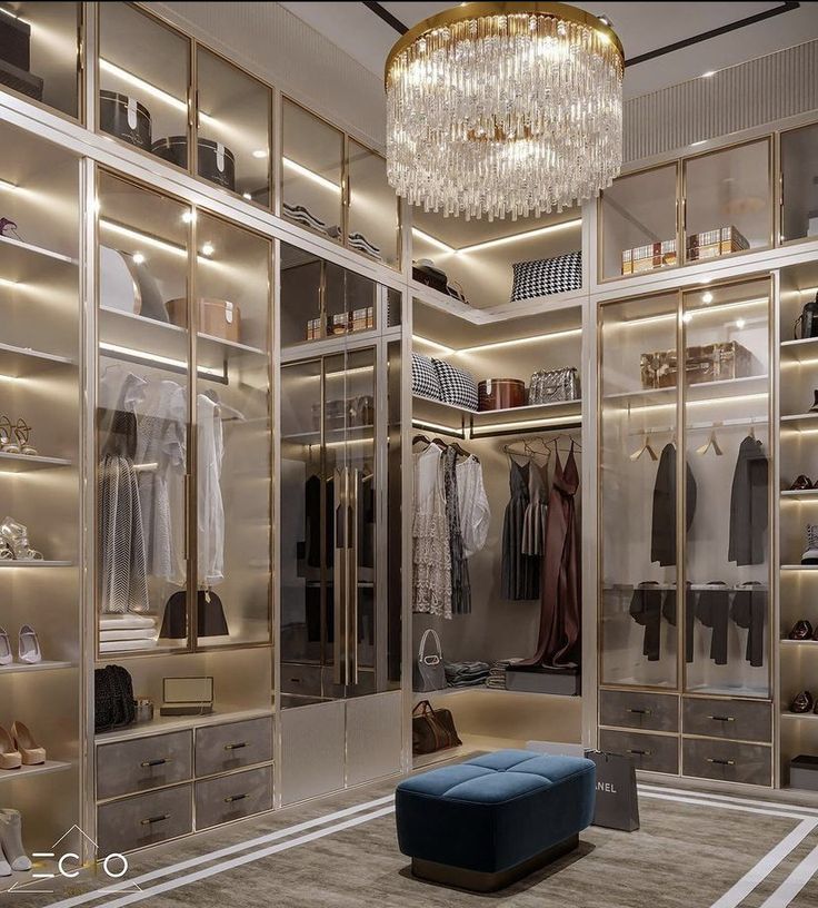 a walk in closet with chandelier and shoes on the shelves, lighting from above