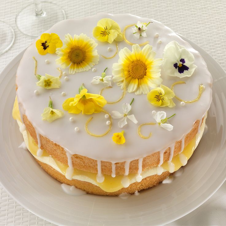 a cake with white frosting and yellow flowers on top is sitting on a plate