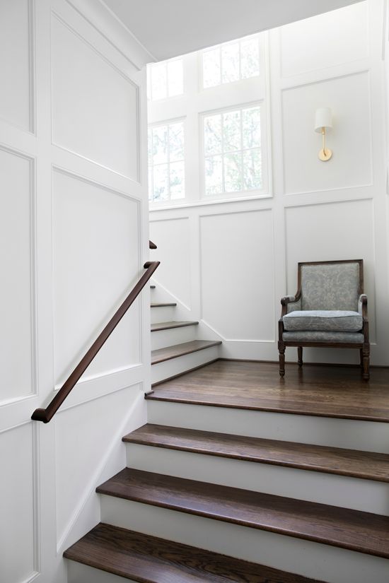 a chair sitting on top of a set of stairs next to a wall with white paneling