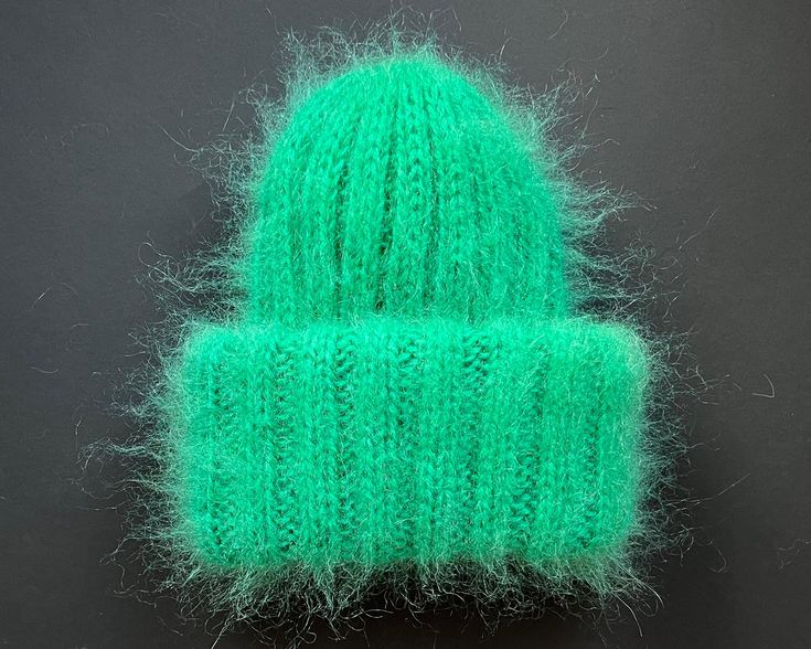 a green knitted hat sitting on top of a table