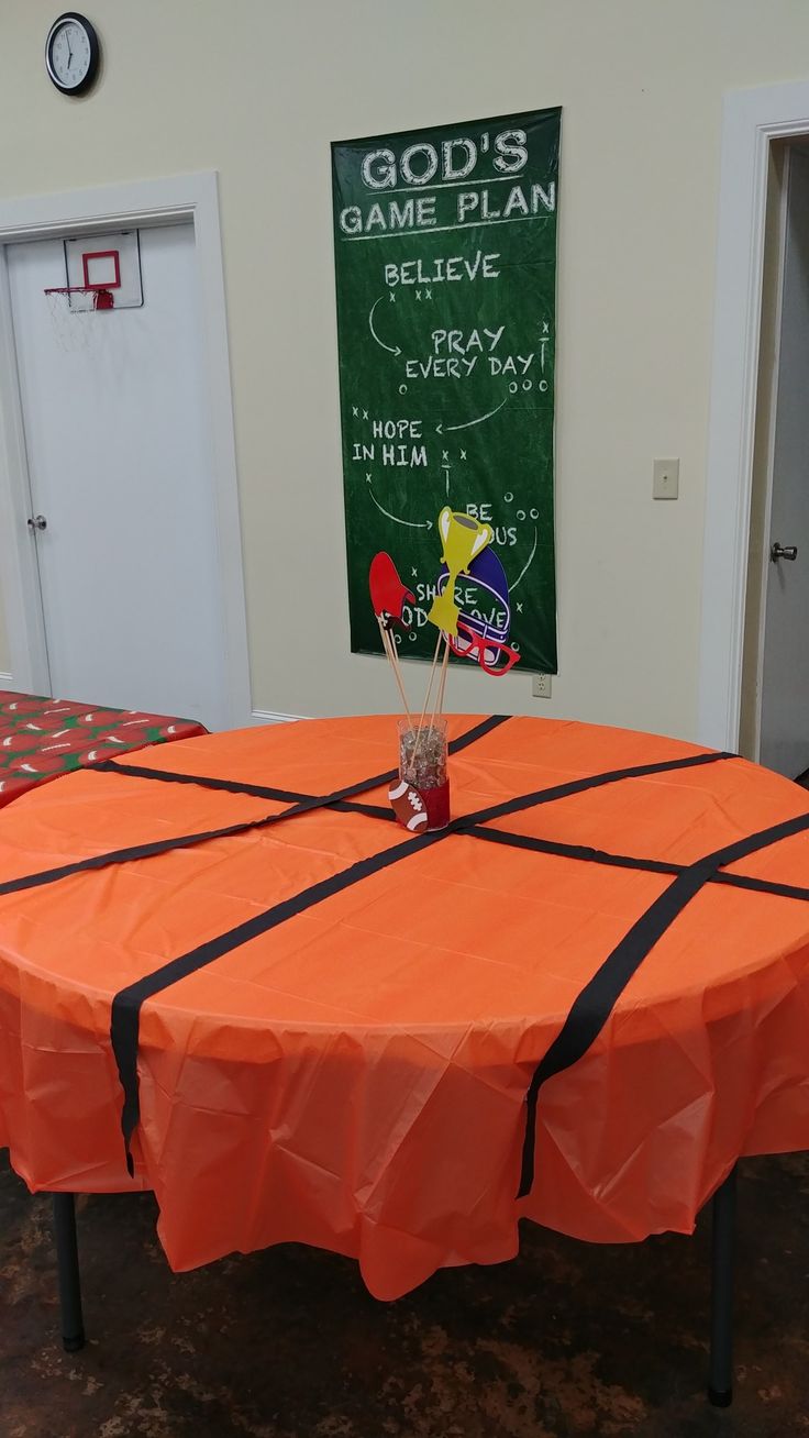 an orange table with black tape around it and a chalkboard on the wall behind it