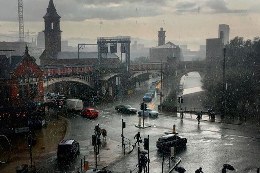 people walking in the rain on a city street with cars and buses driving down it