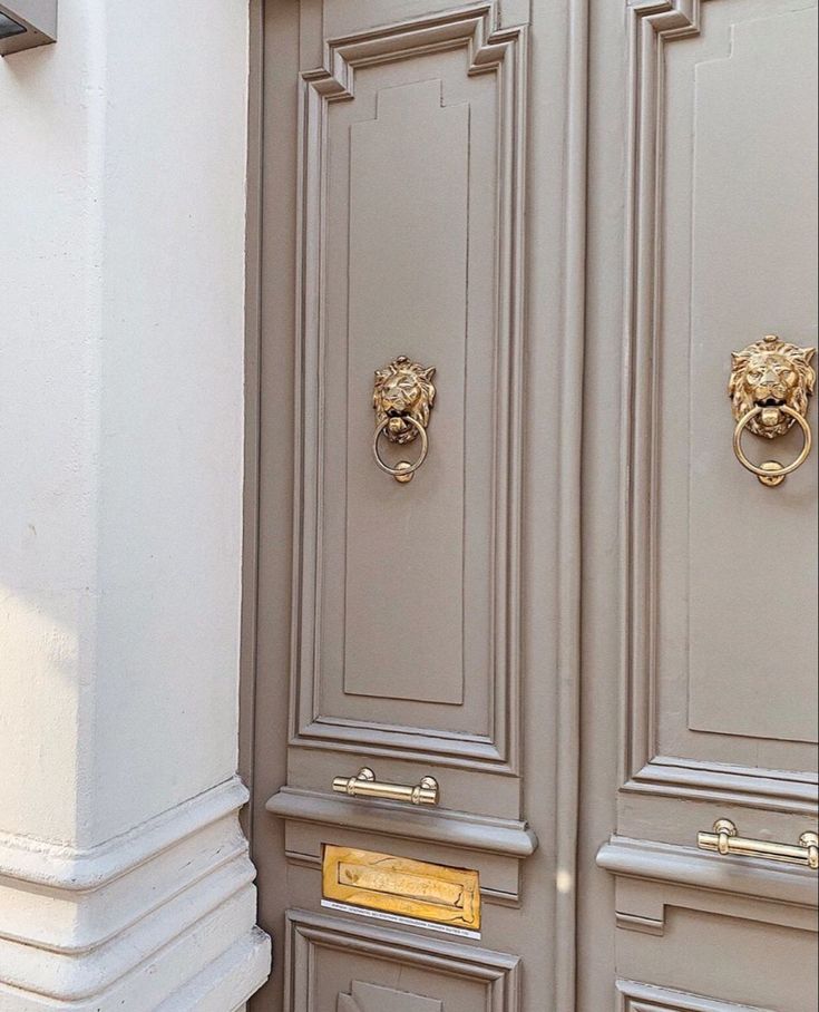 two doors with gold handles and lion heads on the front of them, one is closed