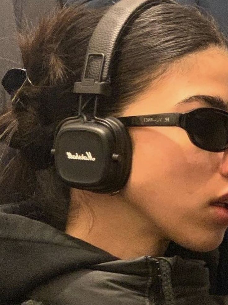 a woman wearing sunglasses and headphones on the subway