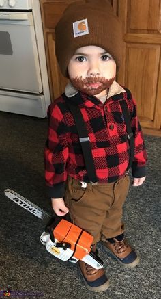 a little boy with a fake mustache on his face standing in front of a stove