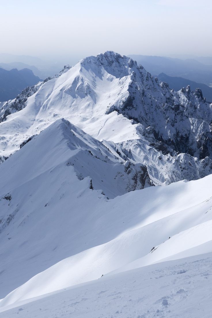 a man riding skis down the side of a snow covered slope on top of a mountain