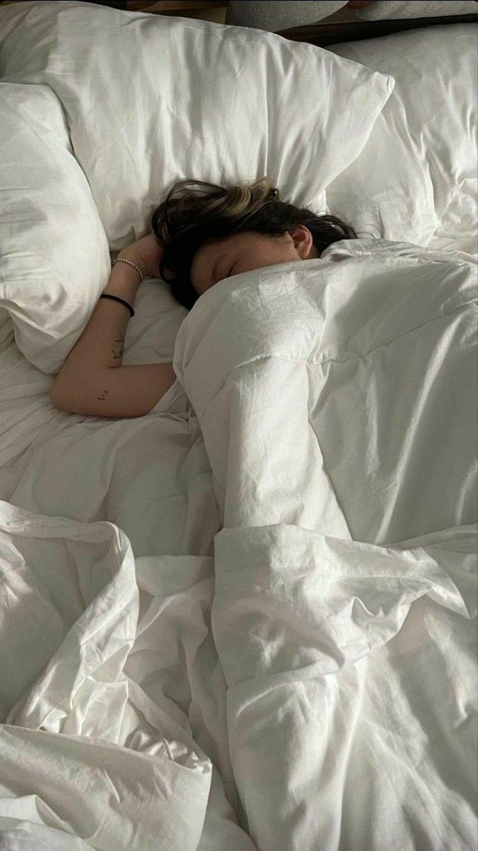 a woman laying in bed with her head on the pillow and she is sleeping peacefully