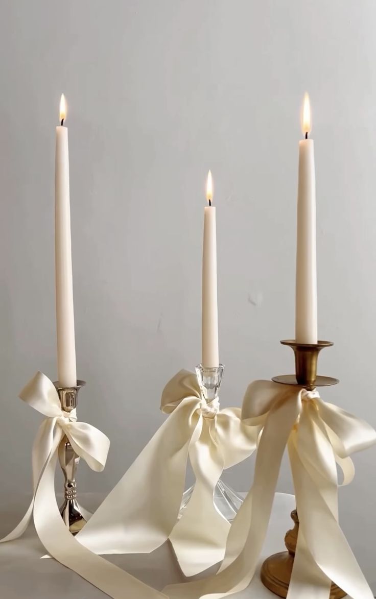 three candles with ribbons on them sitting next to each other