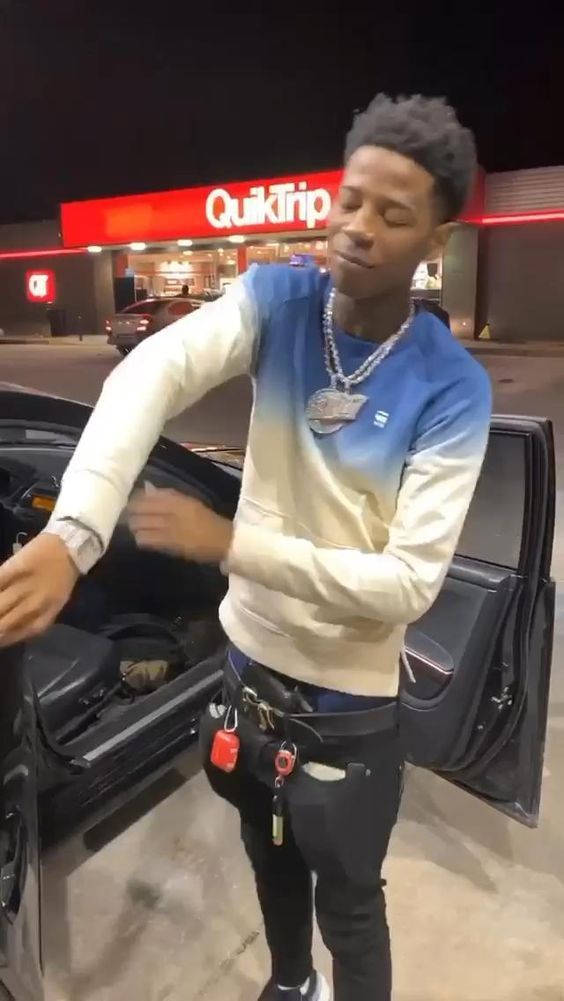 a man standing in front of a car with his hand on the open trunk door