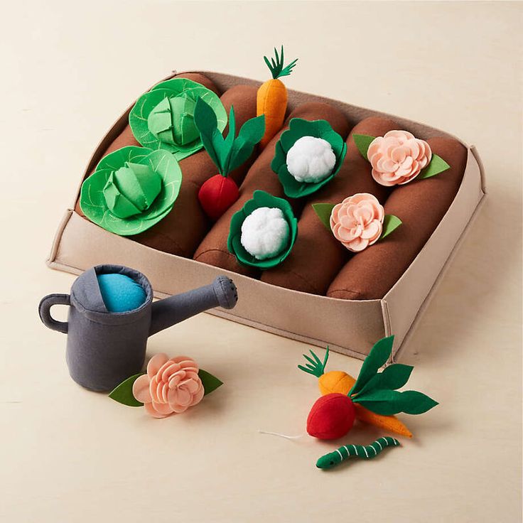 a cardboard box filled with different types of felt flowers and carrots on top of a table