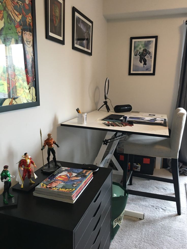 a desk with some toys on top of it in front of two pictures hanging on the wall