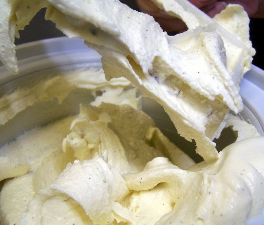 a bowl filled with whipped cream sitting on top of a white table next to a persons hand