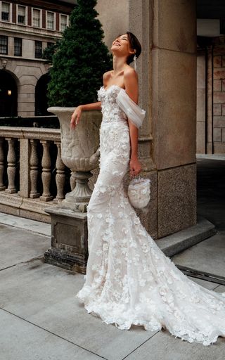 a woman in a wedding dress leaning against a wall