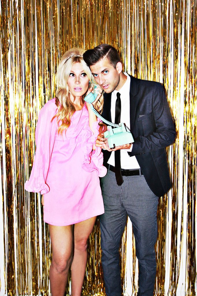 a man and woman posing for a photo in front of gold tinsel backdrops