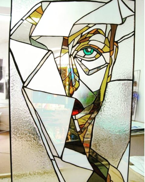 a close up of a stained glass window with a man's face on it