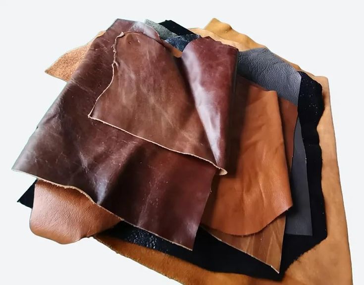 several pieces of leather sitting on top of each other, all different colors and sizes