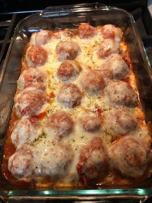 a casserole dish with meatballs and cheese in it on top of the stove