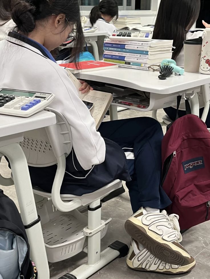 a woman sitting at a table with a book bag