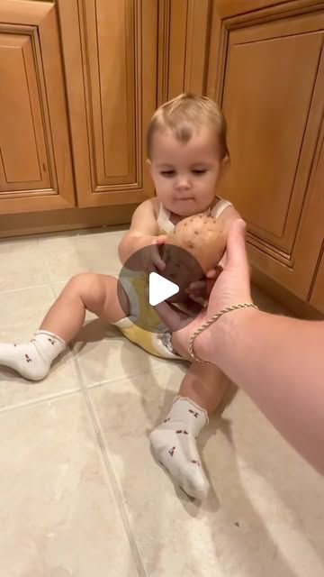 a baby sitting on the floor holding a teddy bear