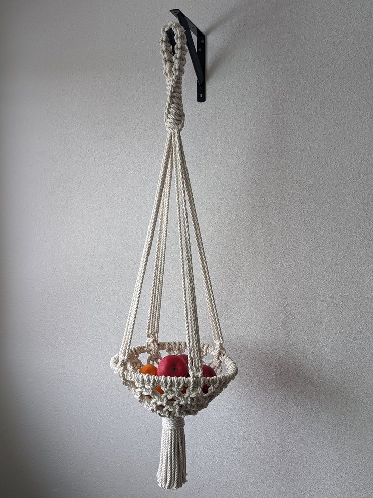 a macrame hanging basket with apples in it