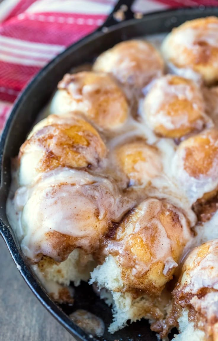 cinnamon rolls in a cast iron skillet on a red and white checkered cloth