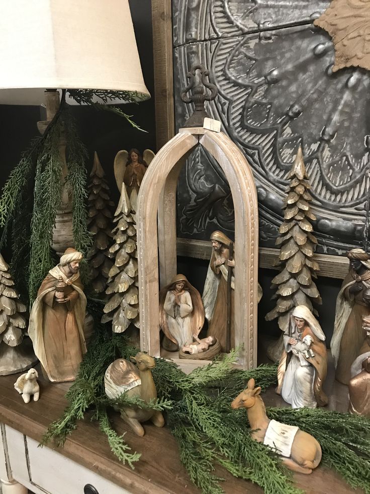 the nativity scene is displayed in front of a lamp and other decorations on a mantle