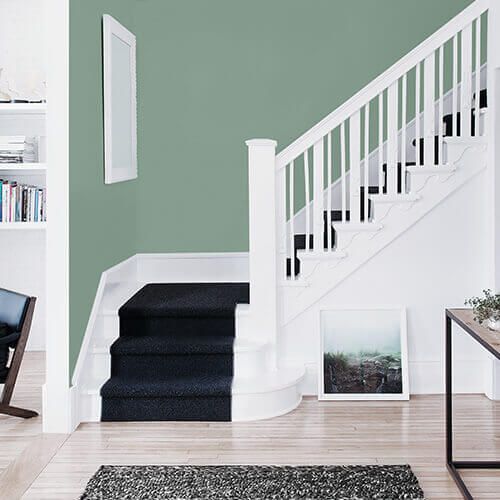 a living room with green walls and white stairs