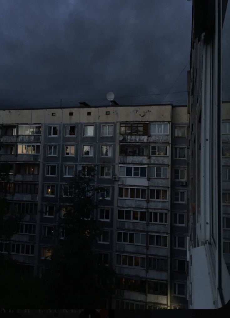 an apartment building is lit up by the dark sky at night, with windows and balconies visible