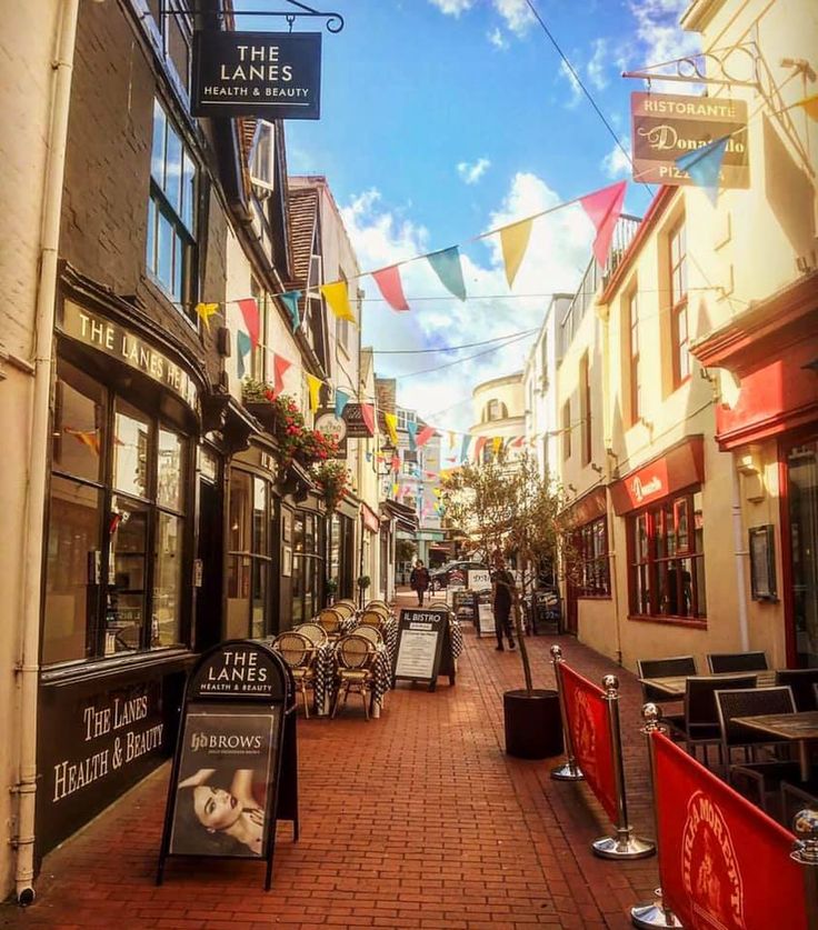 an alley way with tables and chairs lined up along the side walk in front of shops