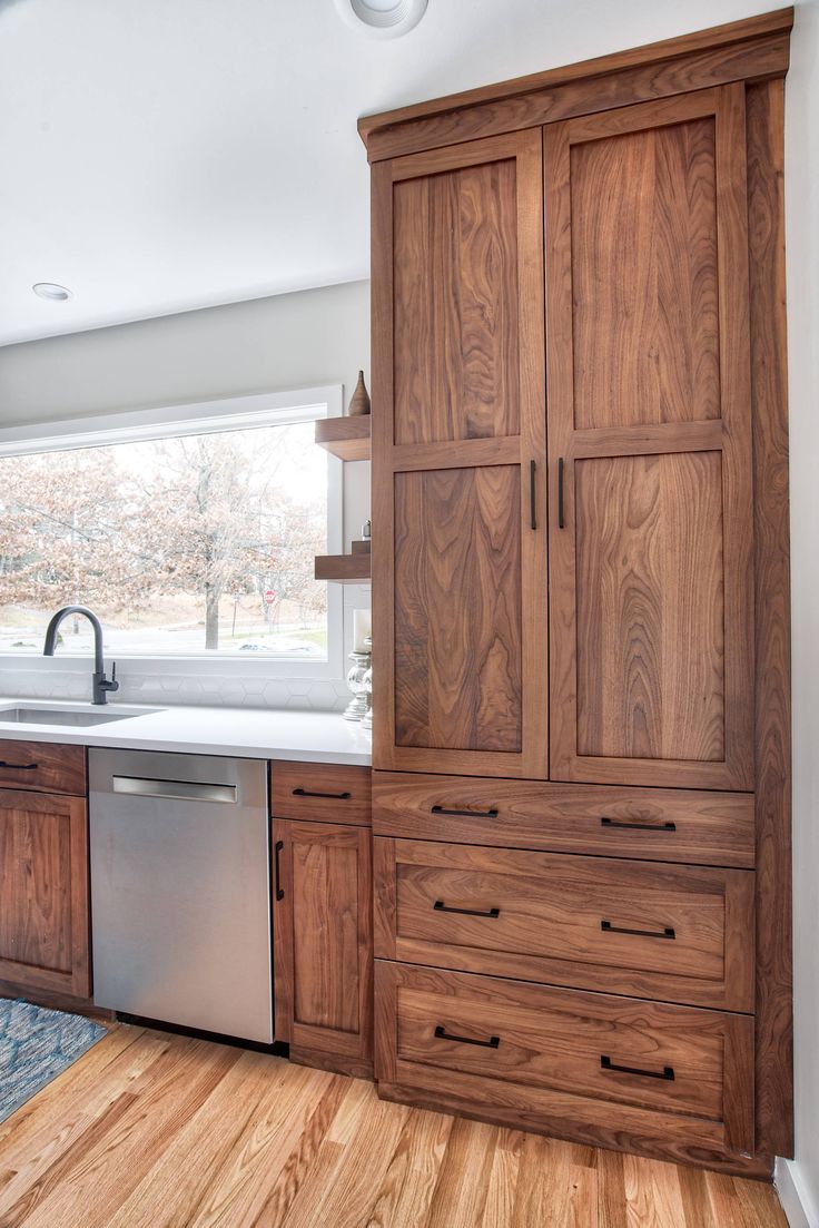 a kitchen with wooden cabinets and stainless steel dishwasher in the center, on hardwood flooring